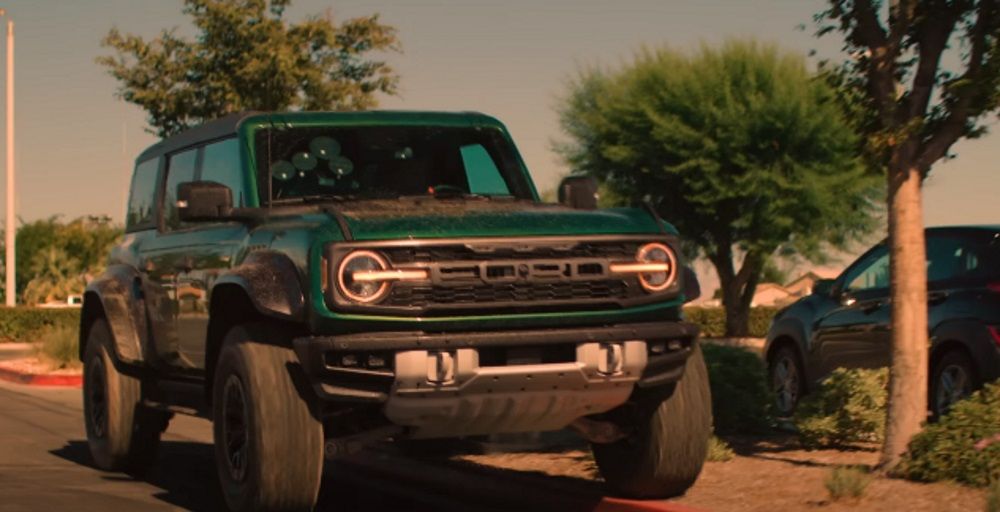 A Ford Bronco Raptor driving over a curb.