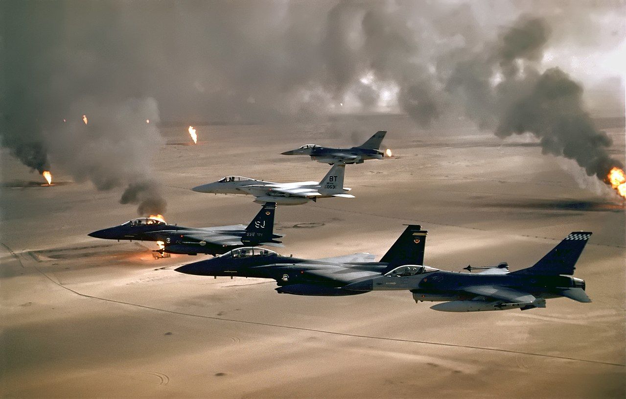 USAF F-15Es, accompanied by an F-15C and two F-16s, flying over burning Kuwaiti oil wells