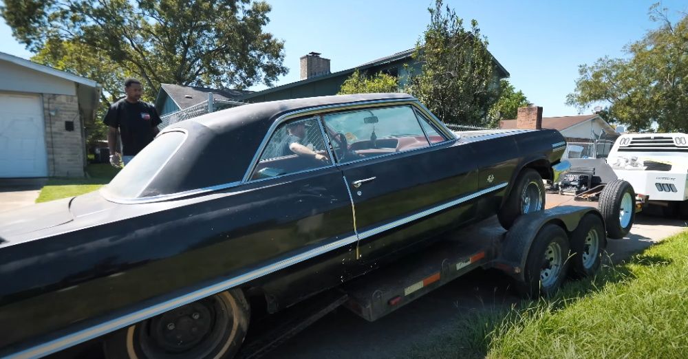 A black 1963 Chevrolet Impala Sport Coupe being loaded on a trailer