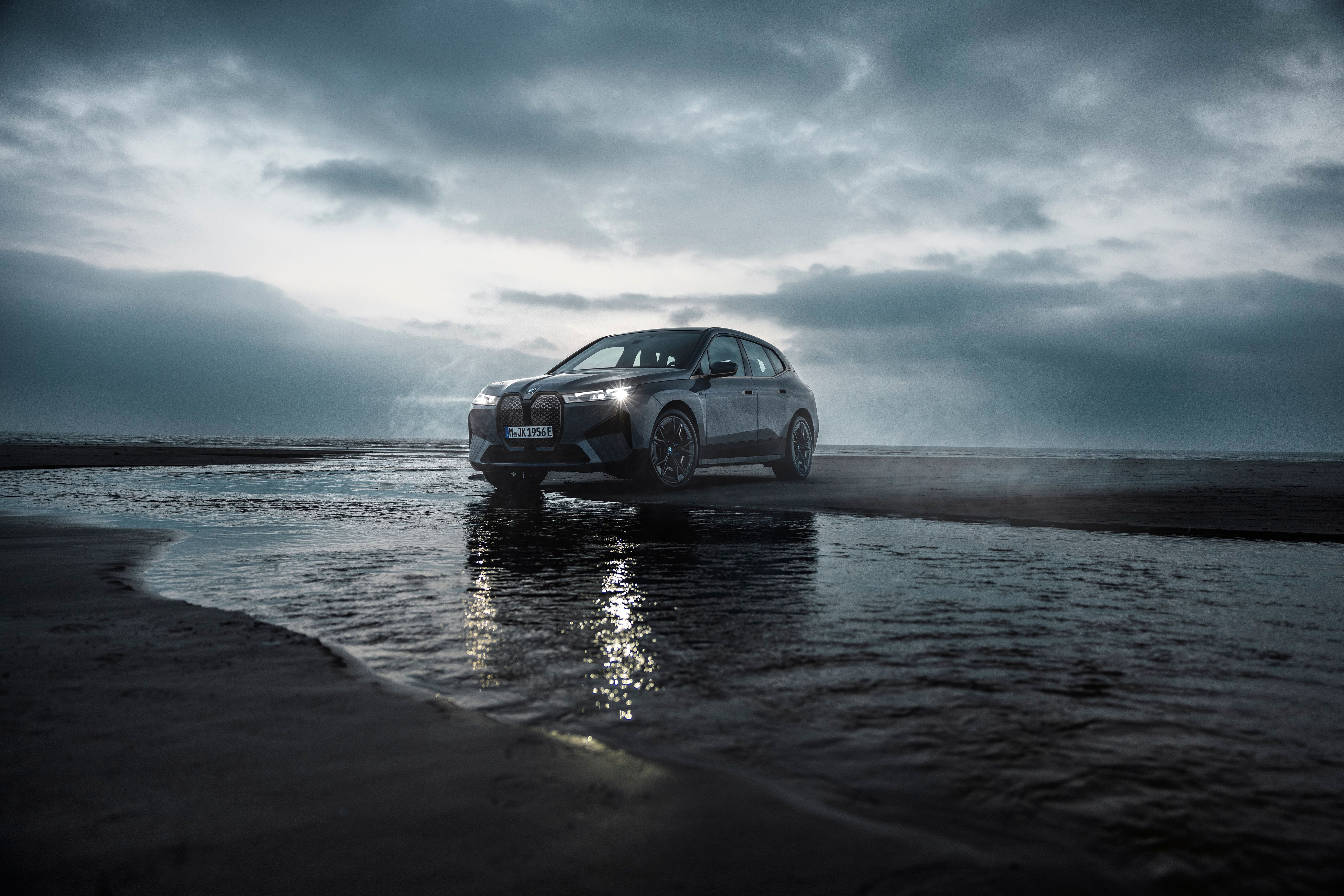 The BMW iX M60 drives on the beach. 