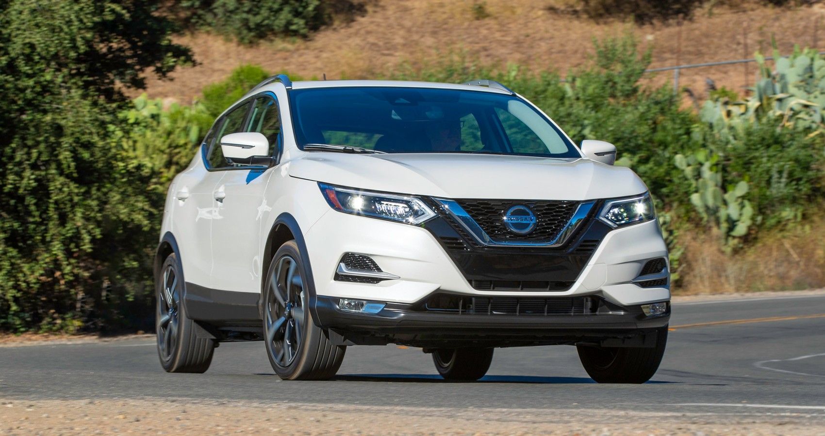 White 2022 Nissan Rogue Sport Driving Around A Bend