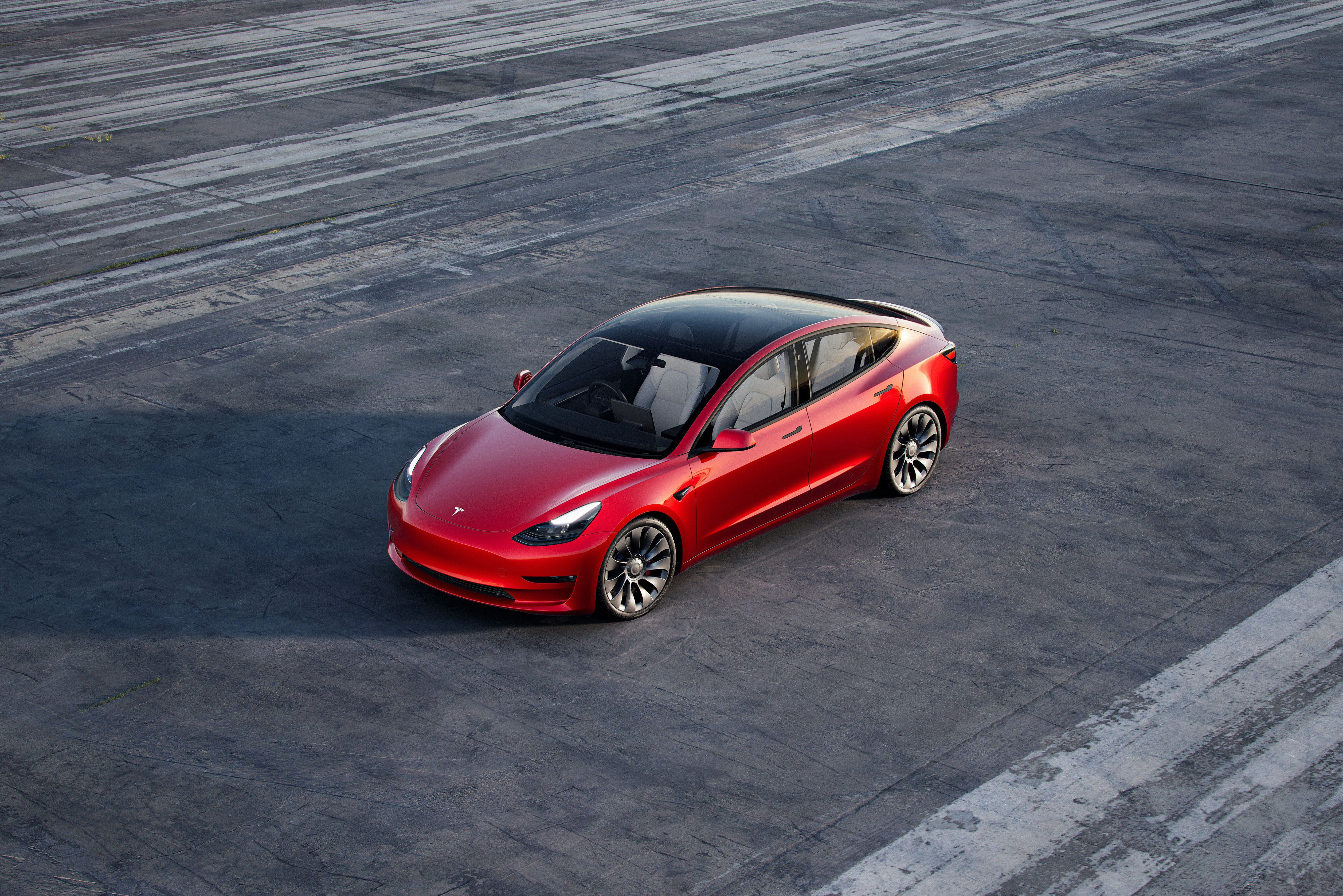 Red 2023 Tesla Model 3 Performance on an empty lot