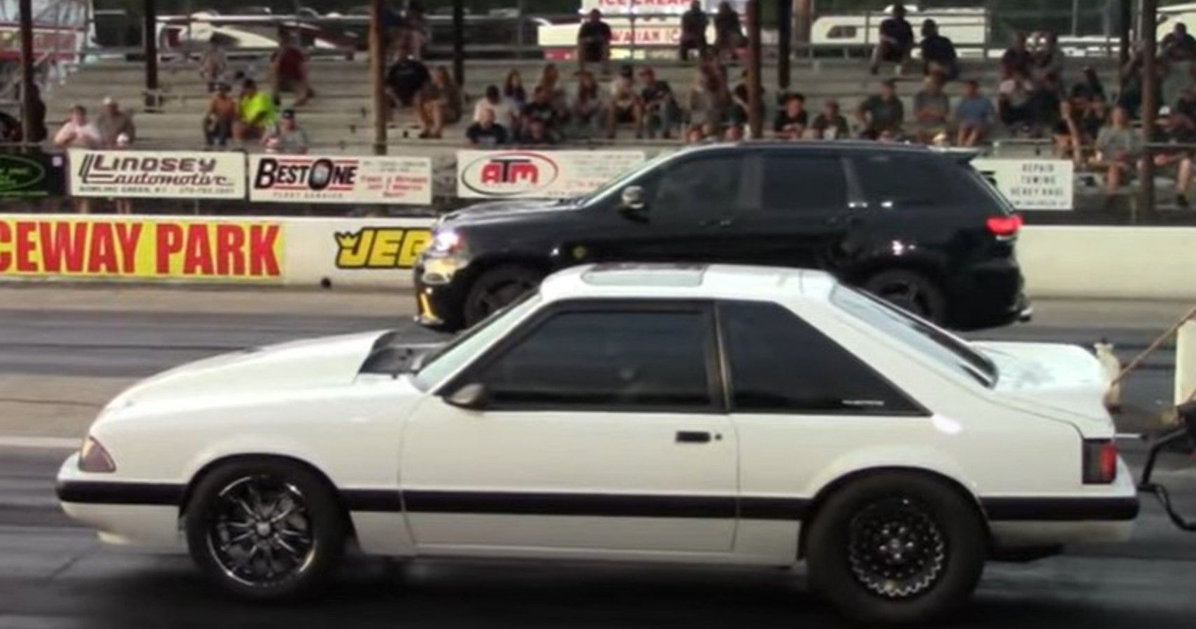Jeep Grand Cherokee Trackhawk next to Fox Body Ford Mustang, drag strip, side