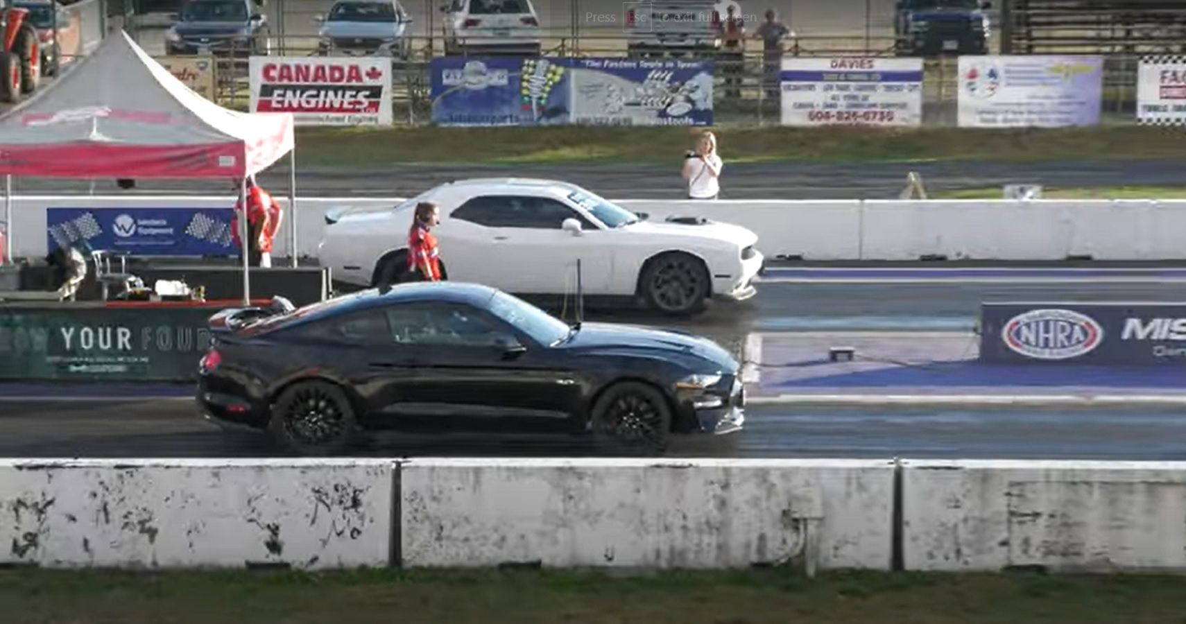 White Dodge Challenger Scat Pack Against A Black Ford Mustang GT At the Drag Strip