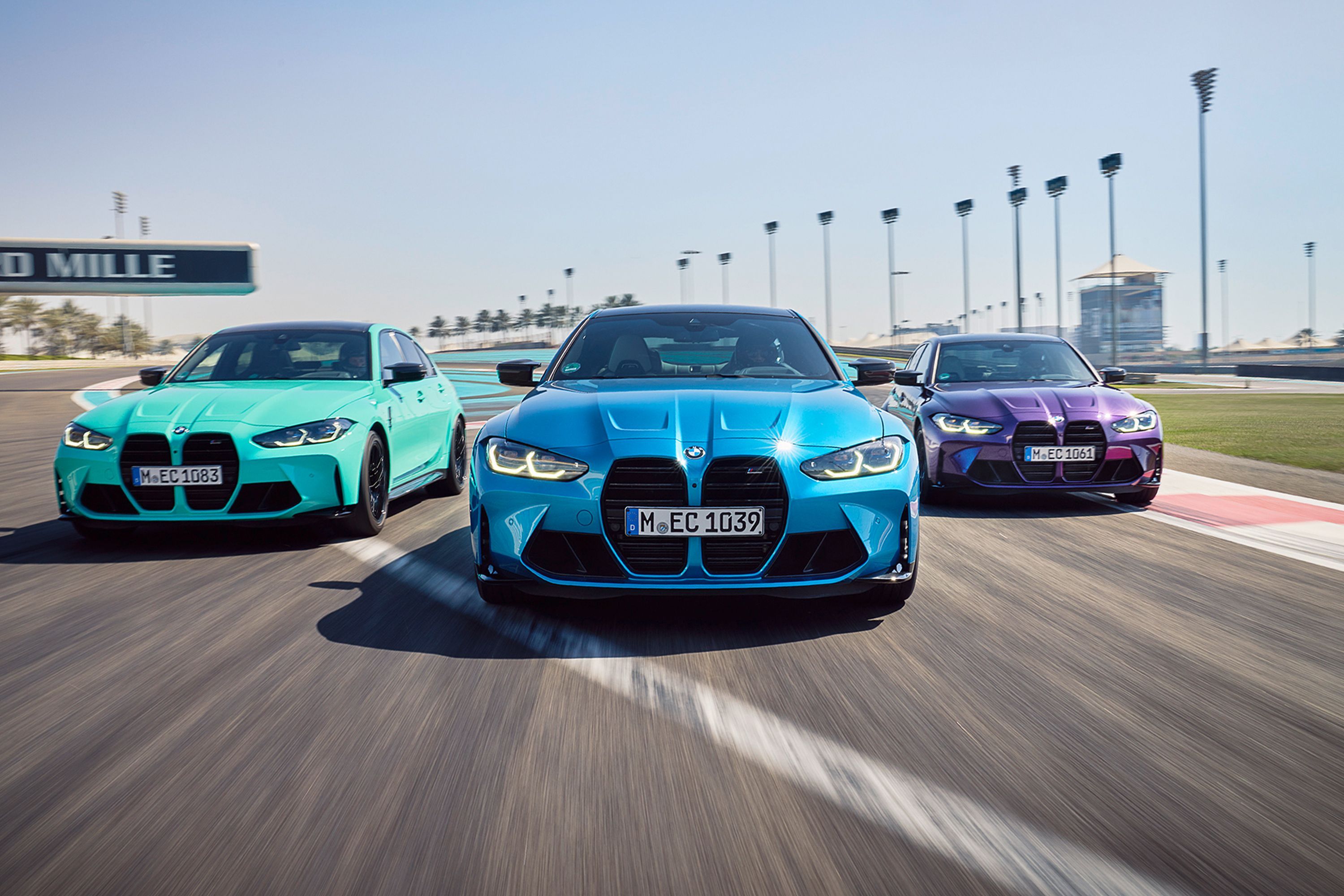 Un trío formado por un BMW M3 y M4 azul, turquesa y morado en el circuito de Yas Marina