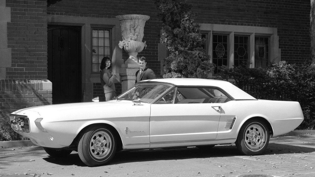 A white 1963 Ford Mustang II concept parked in front of a house