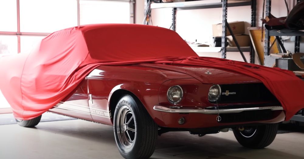 A red 1967 Ford Shelby Mustang GT500 under a cover 