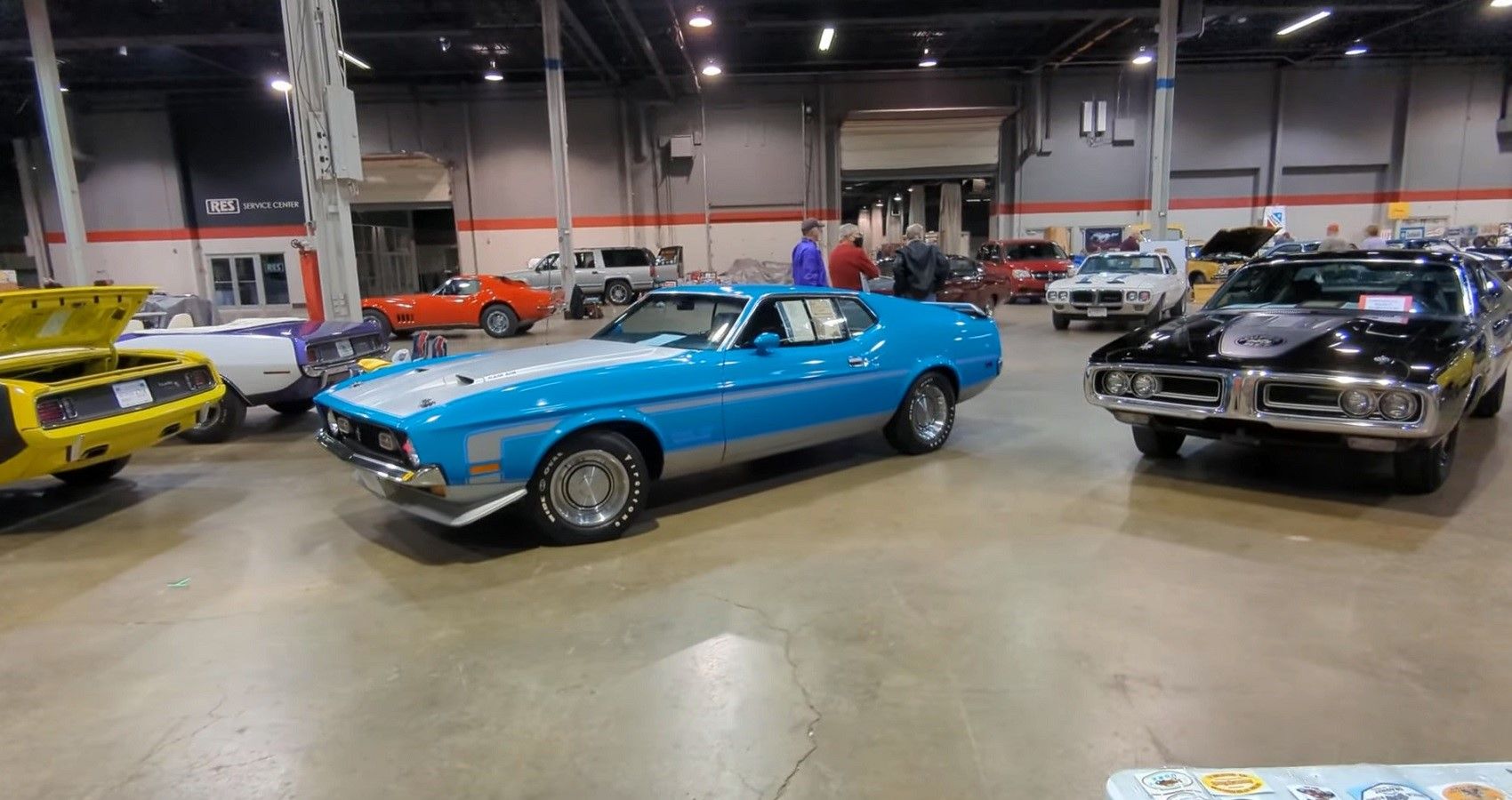 Muscle cars, sports cars and more lined up in well-lit hangar