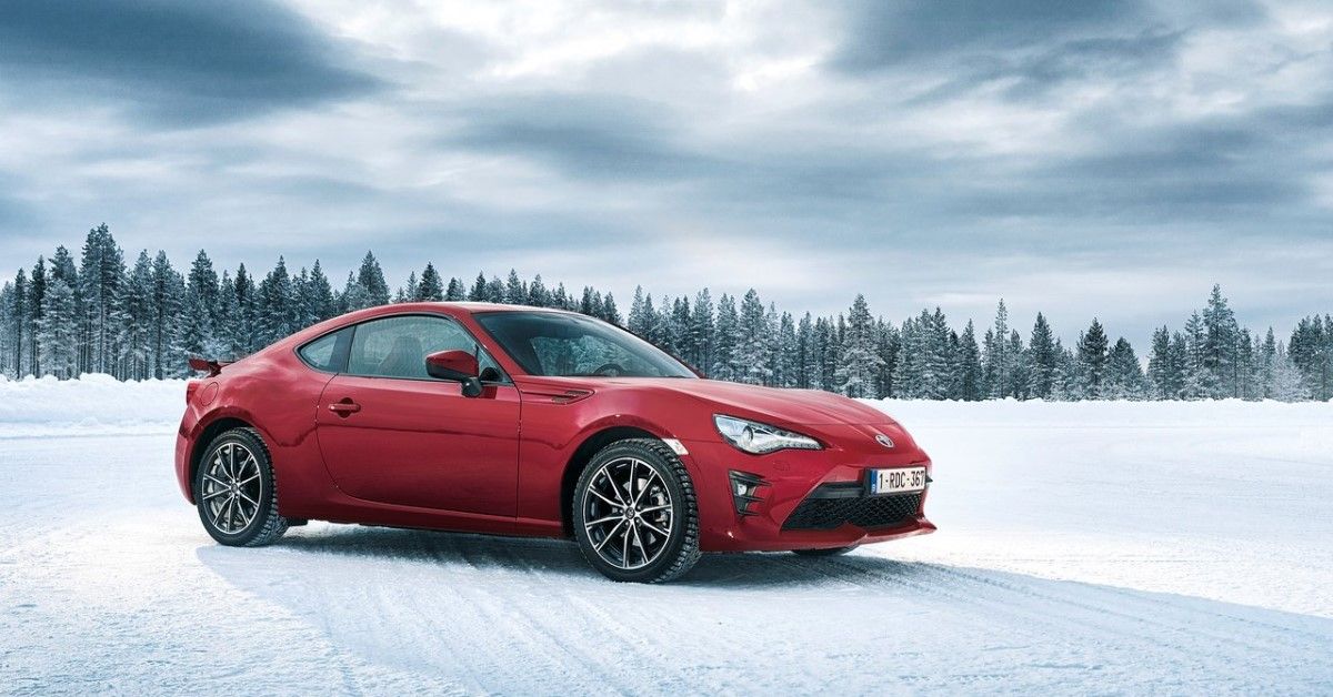 A red 2017 Toyota GT86 in the third quarter cinematic sports car wallpaper view in front of the snow