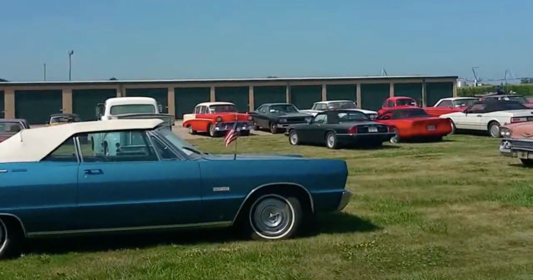 Abandoned Car Museum contents, cars lined up on field, garages in background