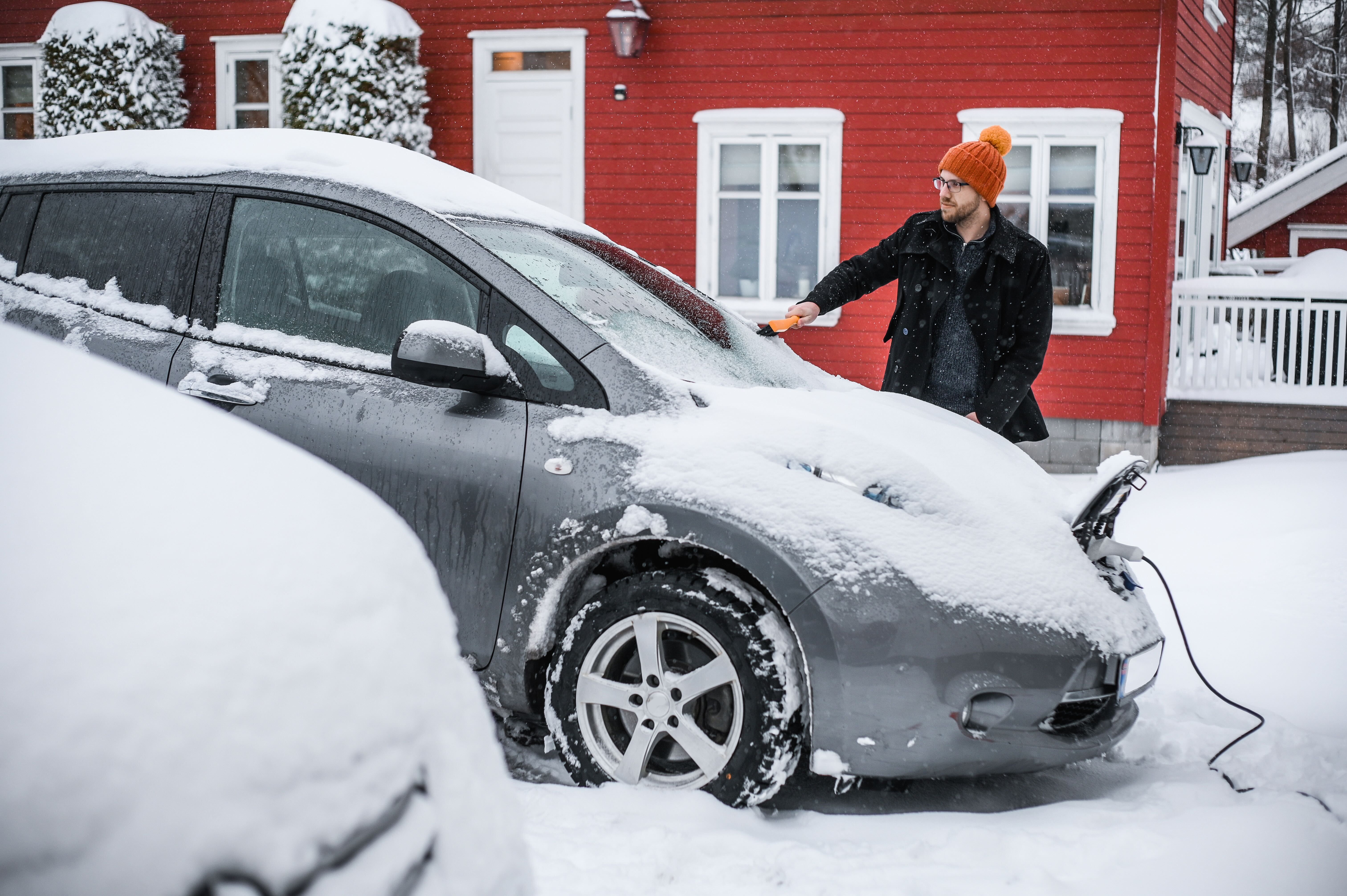 Man charging electric car in the snow