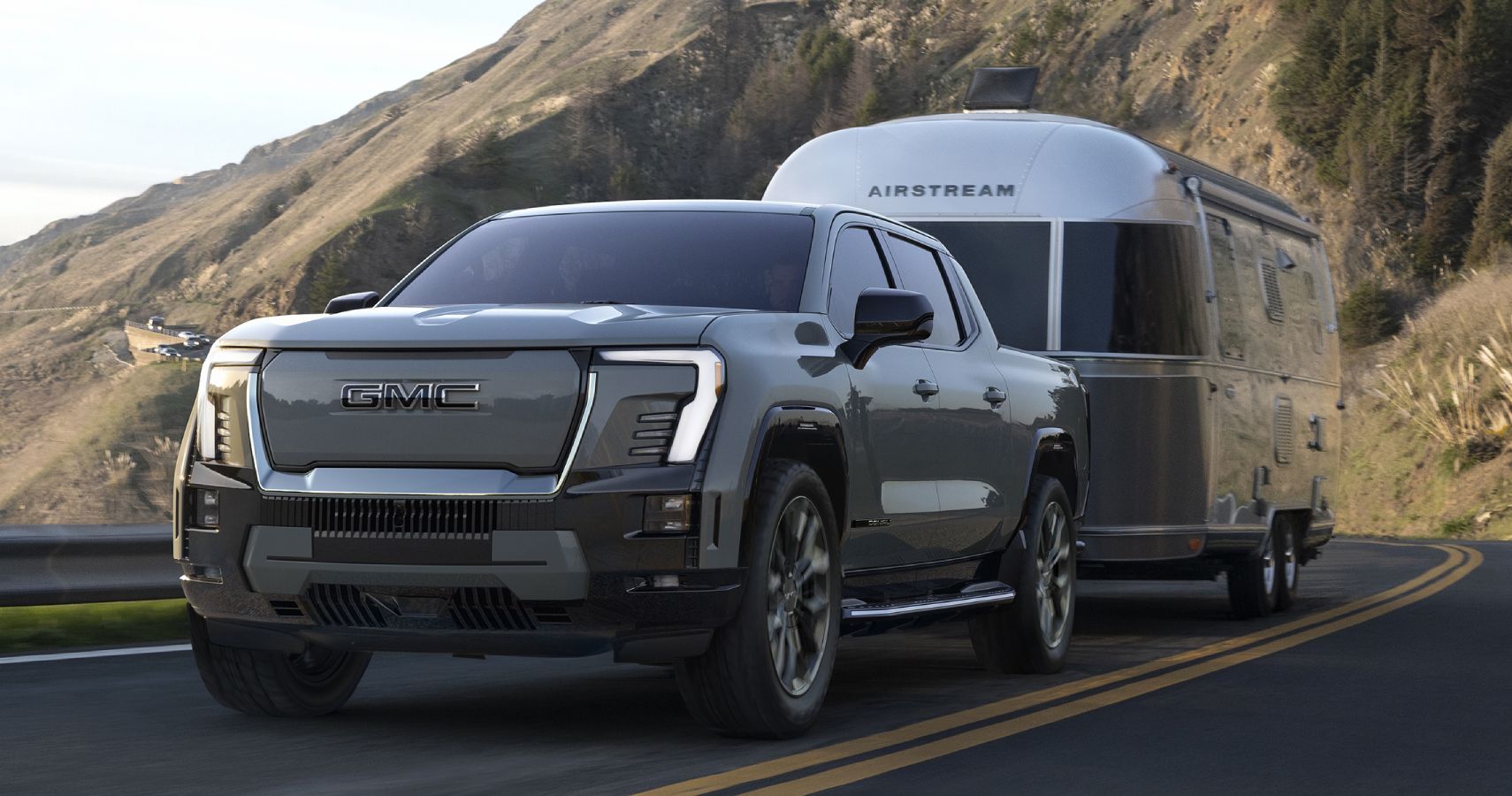 Gray 2024 GMC Sierra EV driven on the road with a trailer attached to it