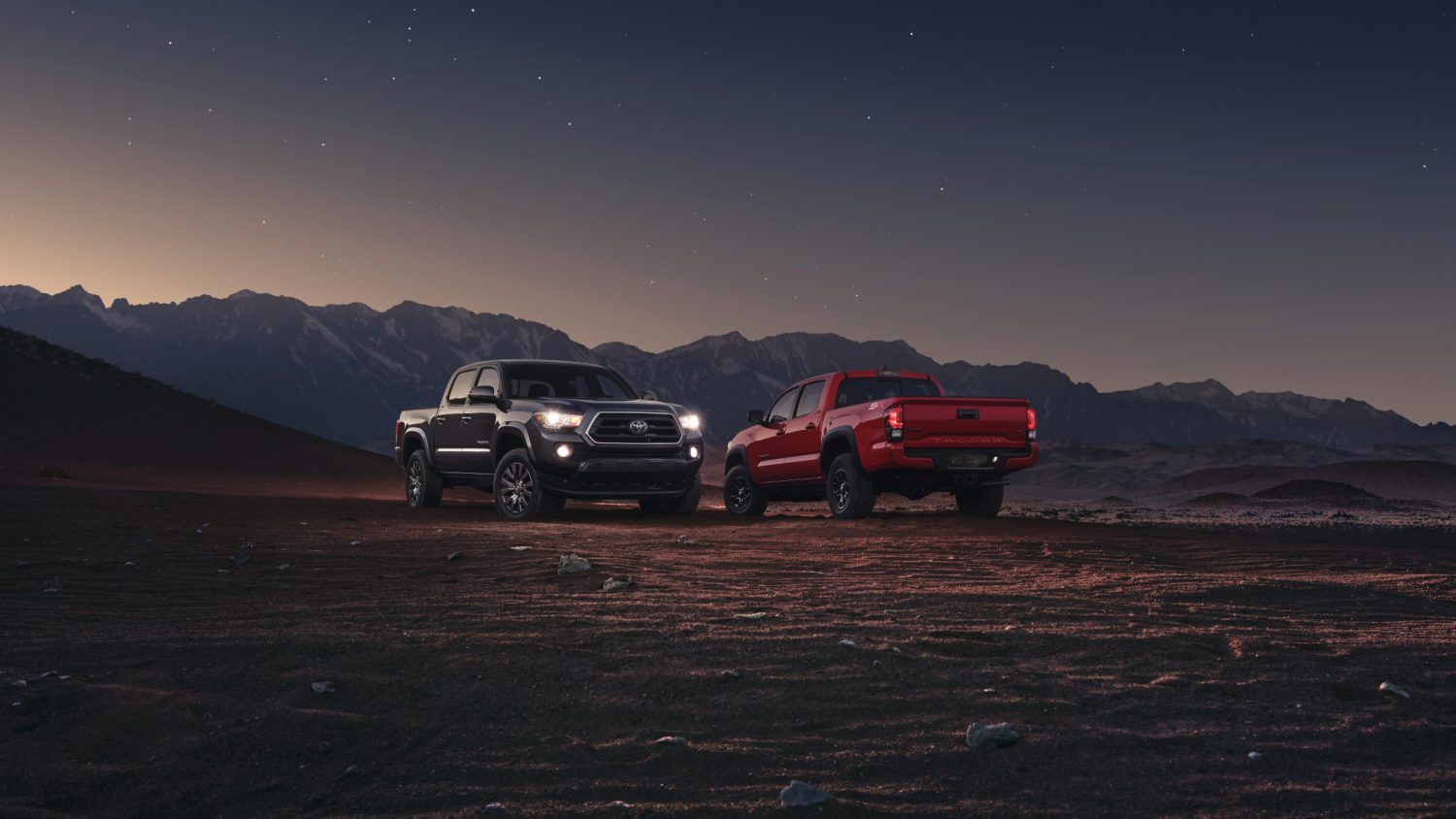 Two 2023 Toyota Tacomas in the desert at dusk