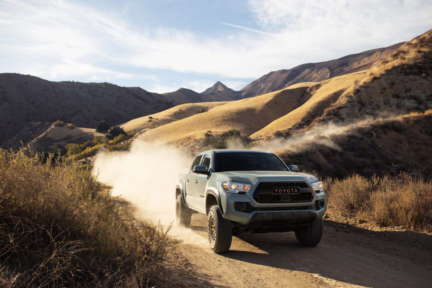 2023 Toyota Tacoma powering up a hill with a cloud of dust behind it