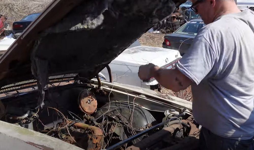 Steve Magnante checks out the engine bay of a junkyard 1971 Chevrolet Monte Carlo