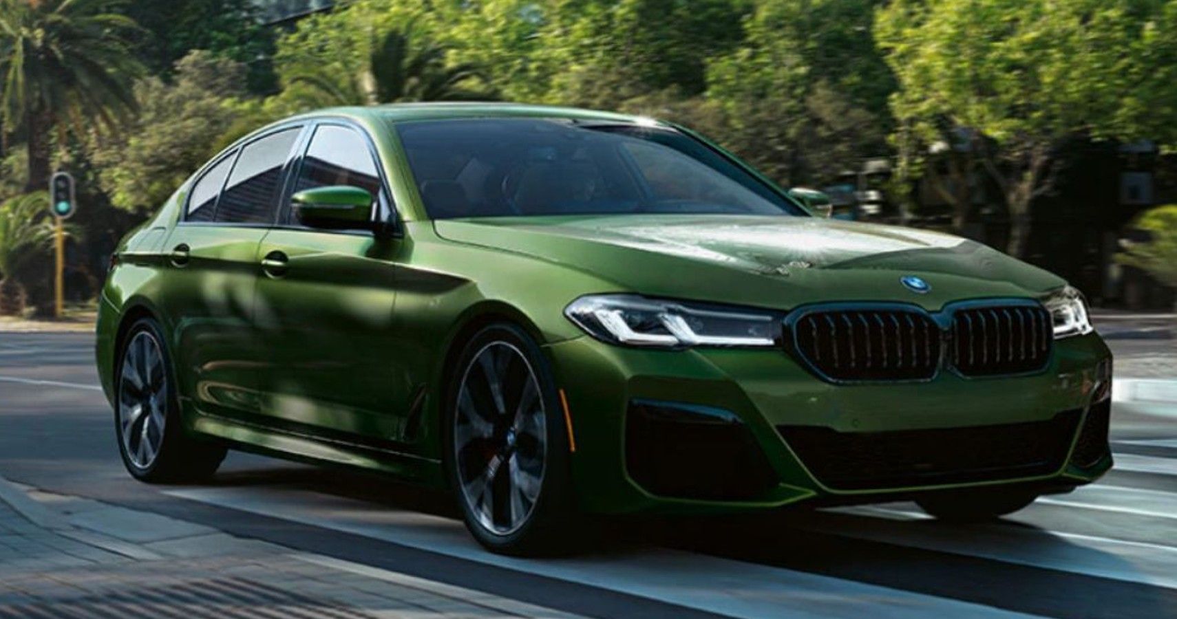 Green 2023 BMW 5 Series Sedan on the road