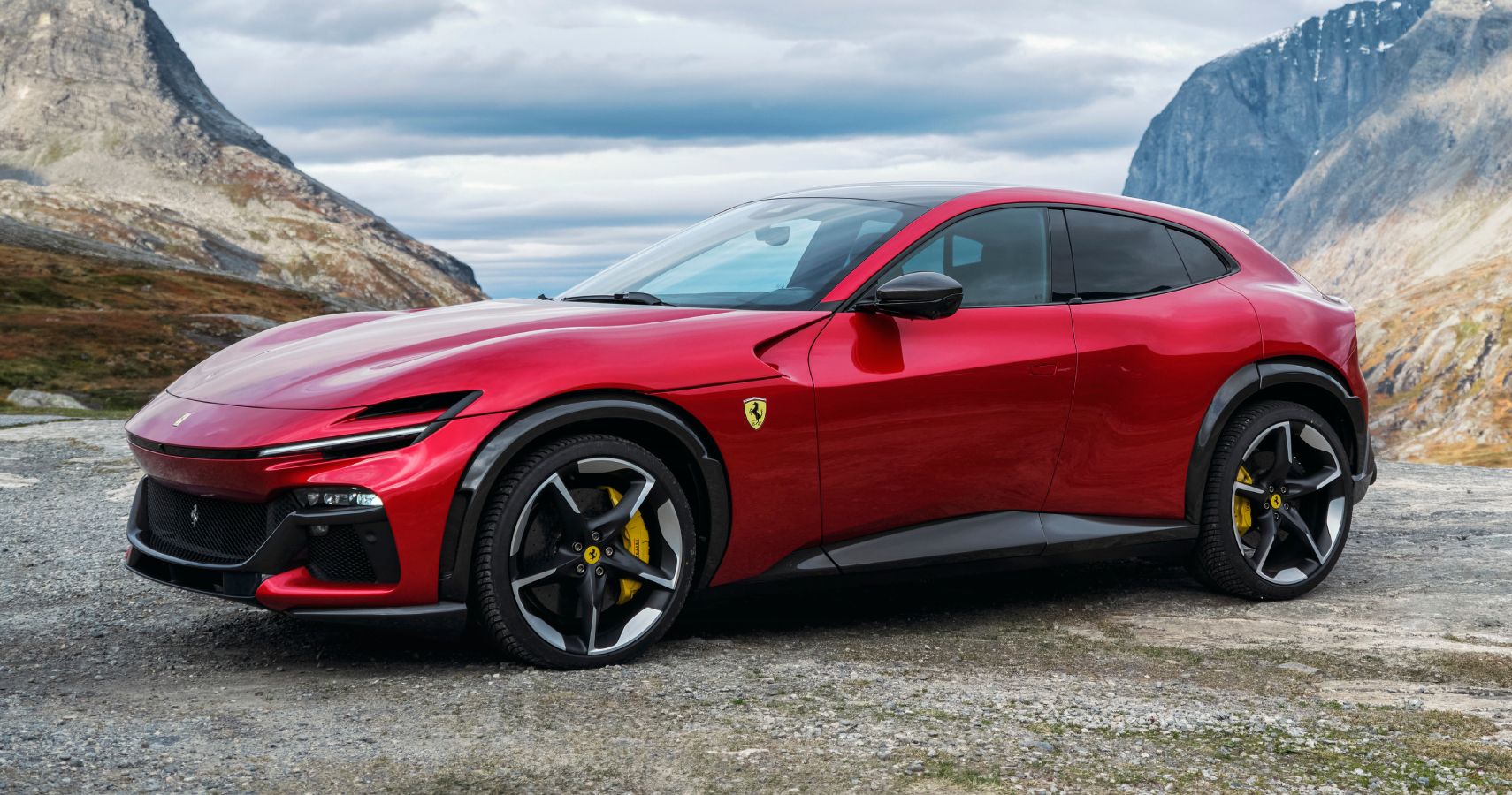 A red Ferrari Purosangue is parked in the open air