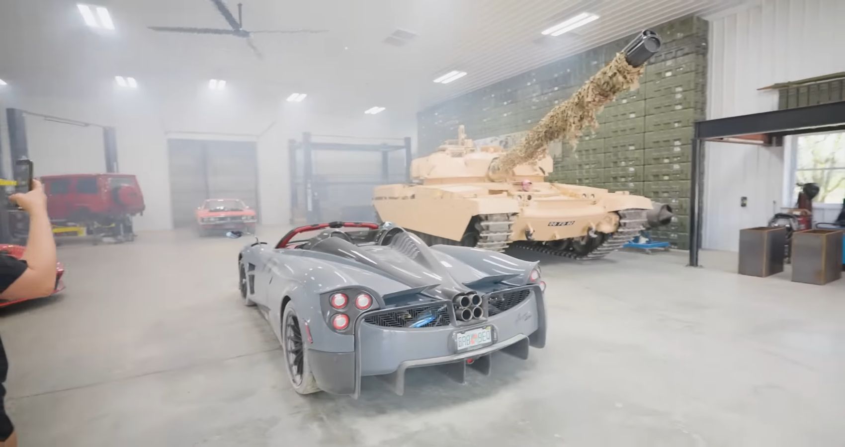 A blue Pagani Huayra Roadster and a sandstorm M1 Abrams Tank