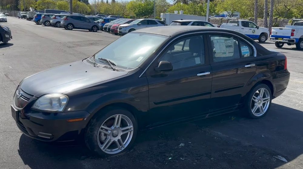 Side view of a black 2012 CODA sedan in a dealership storage lot