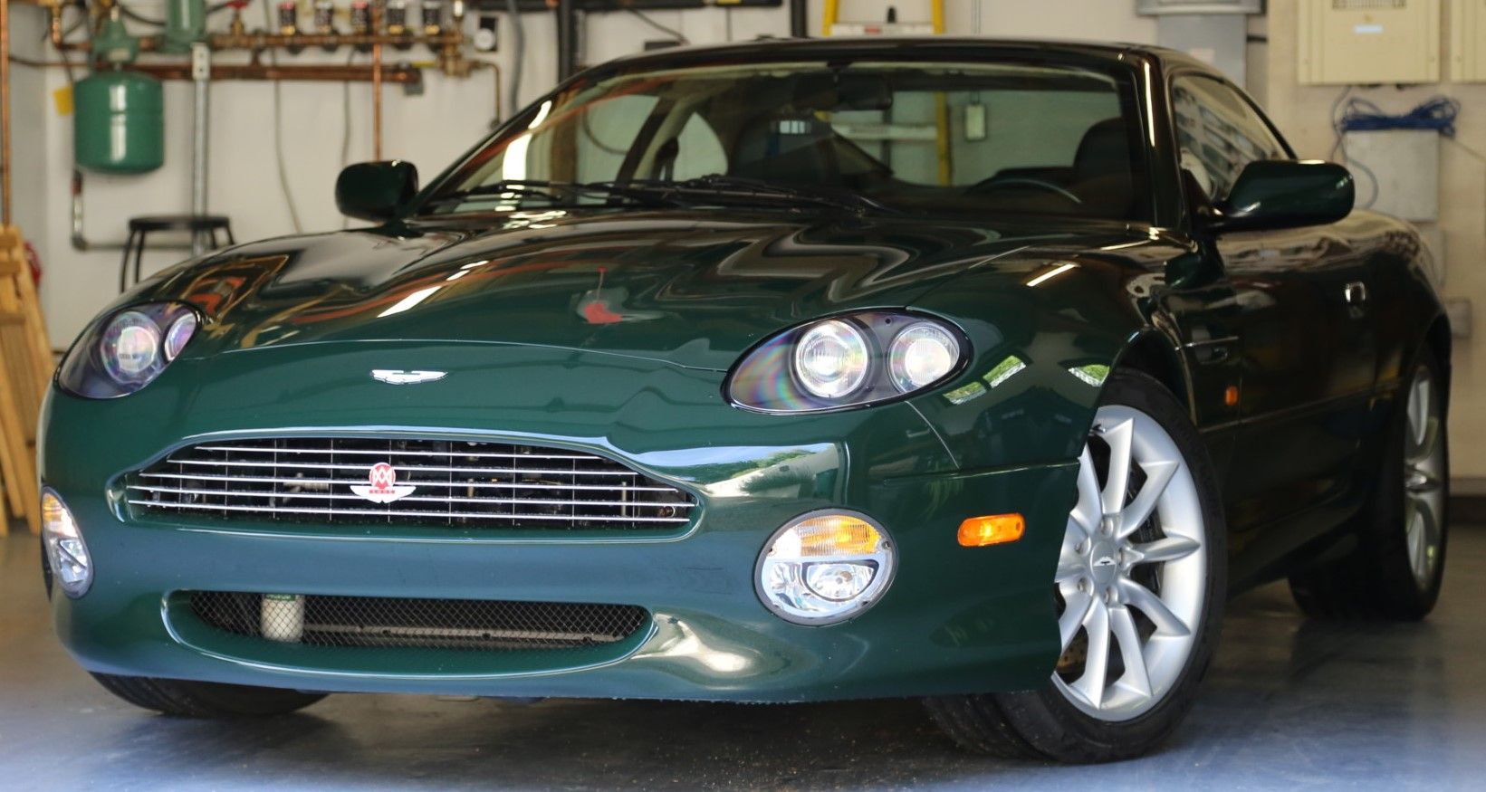 Green ​​​​​​​Aston Martin DB7 estacionado dentro de casa