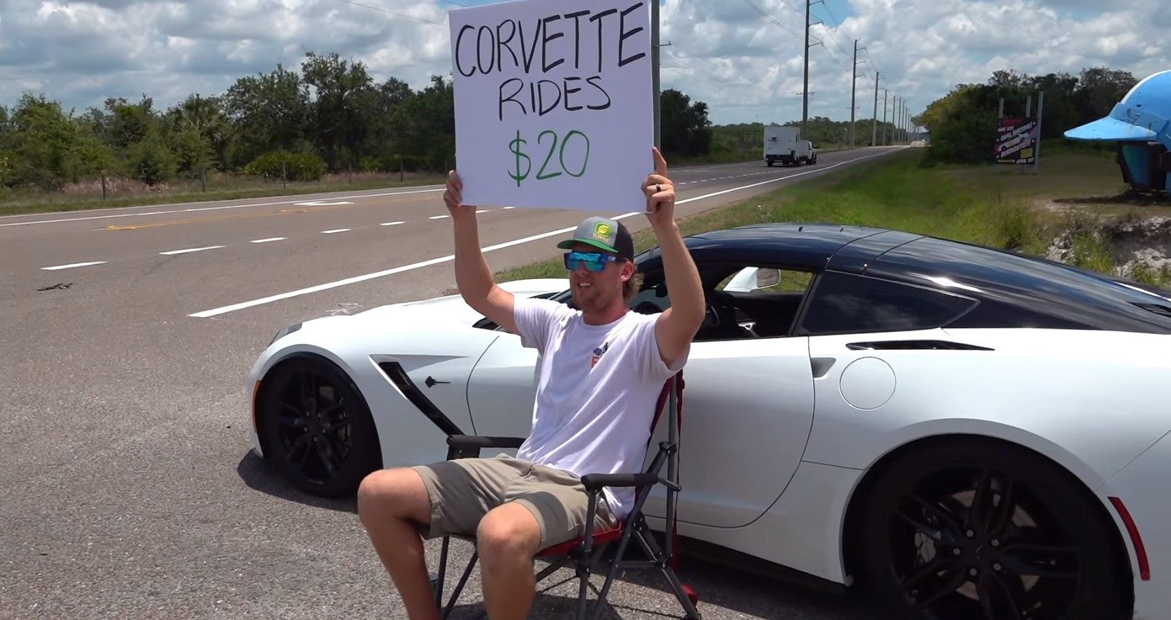 Cleetus McFarland Chevrolet Corvette rides stand, Cleetus sitting infront of car with sign
