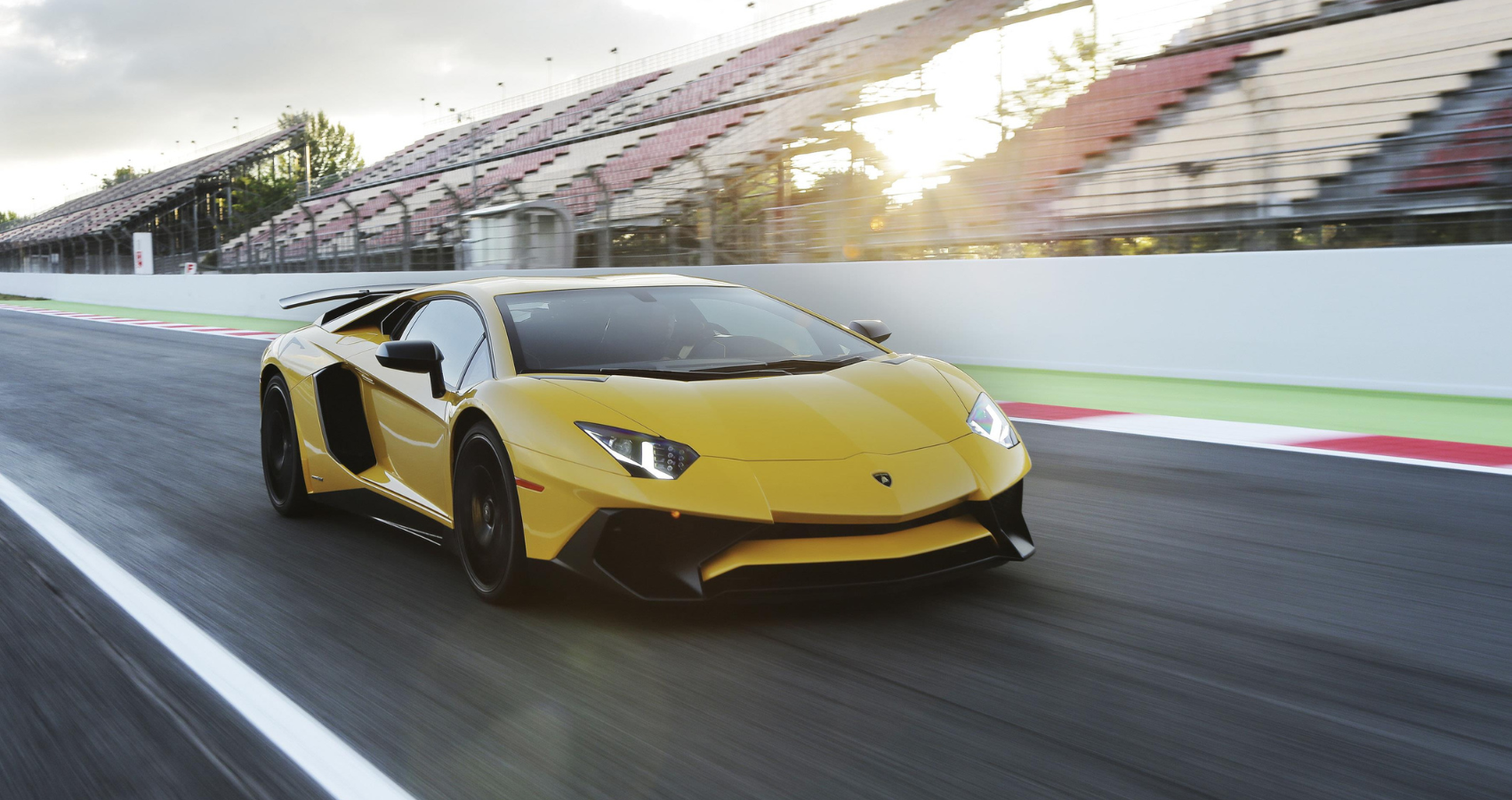 Yellow Lamborghini Aventador LP750-4 SV on a race track passing the stand