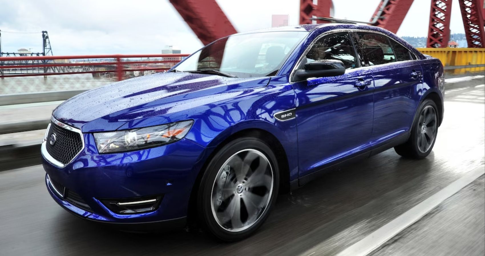 2019 Ford Taurus SHO em azul dirigindo no molhado através de uma ponte