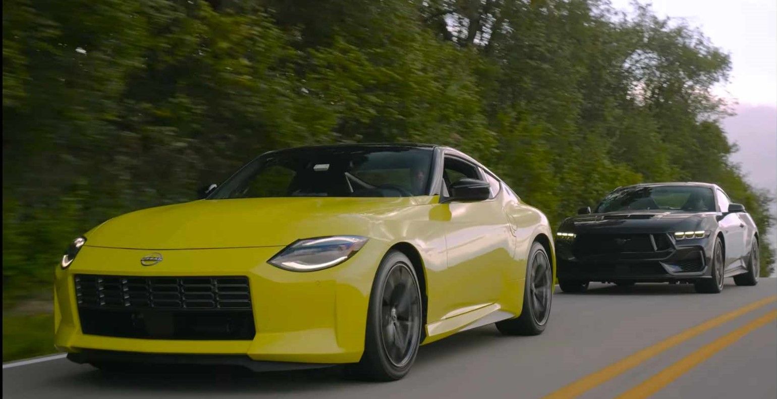 Um Nissan Z amarelo e um Ford Mustang GT preto estão sendo conduzidos em uma estrada.
