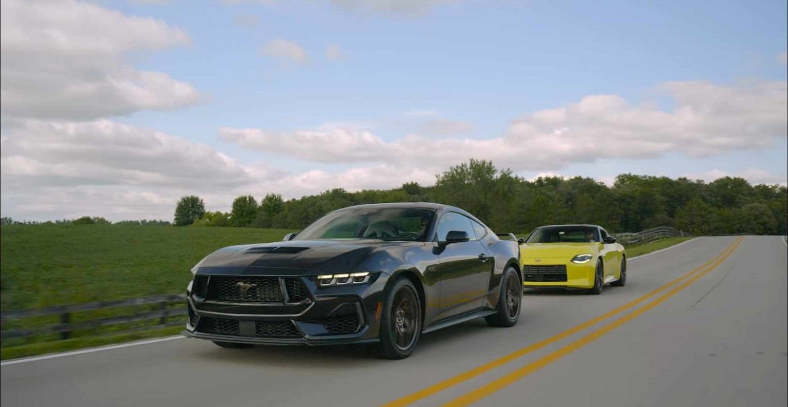Um Ford Mustang GT preto e um Nissan Z amarelo circulam numa estrada rural.