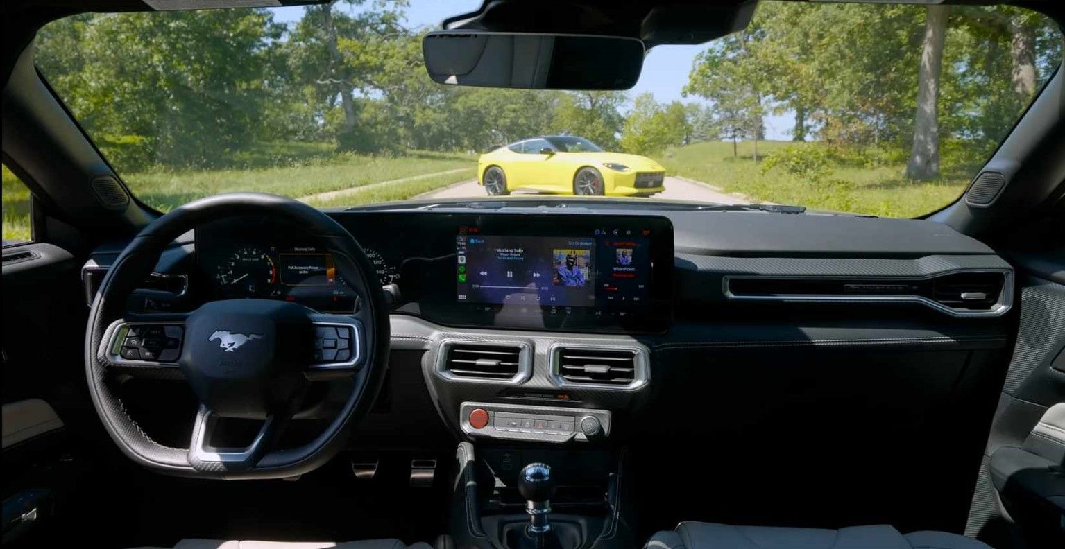 Interior do Ford Mustang GT 2024 com um Nissan Z 2023 amarelo à distância