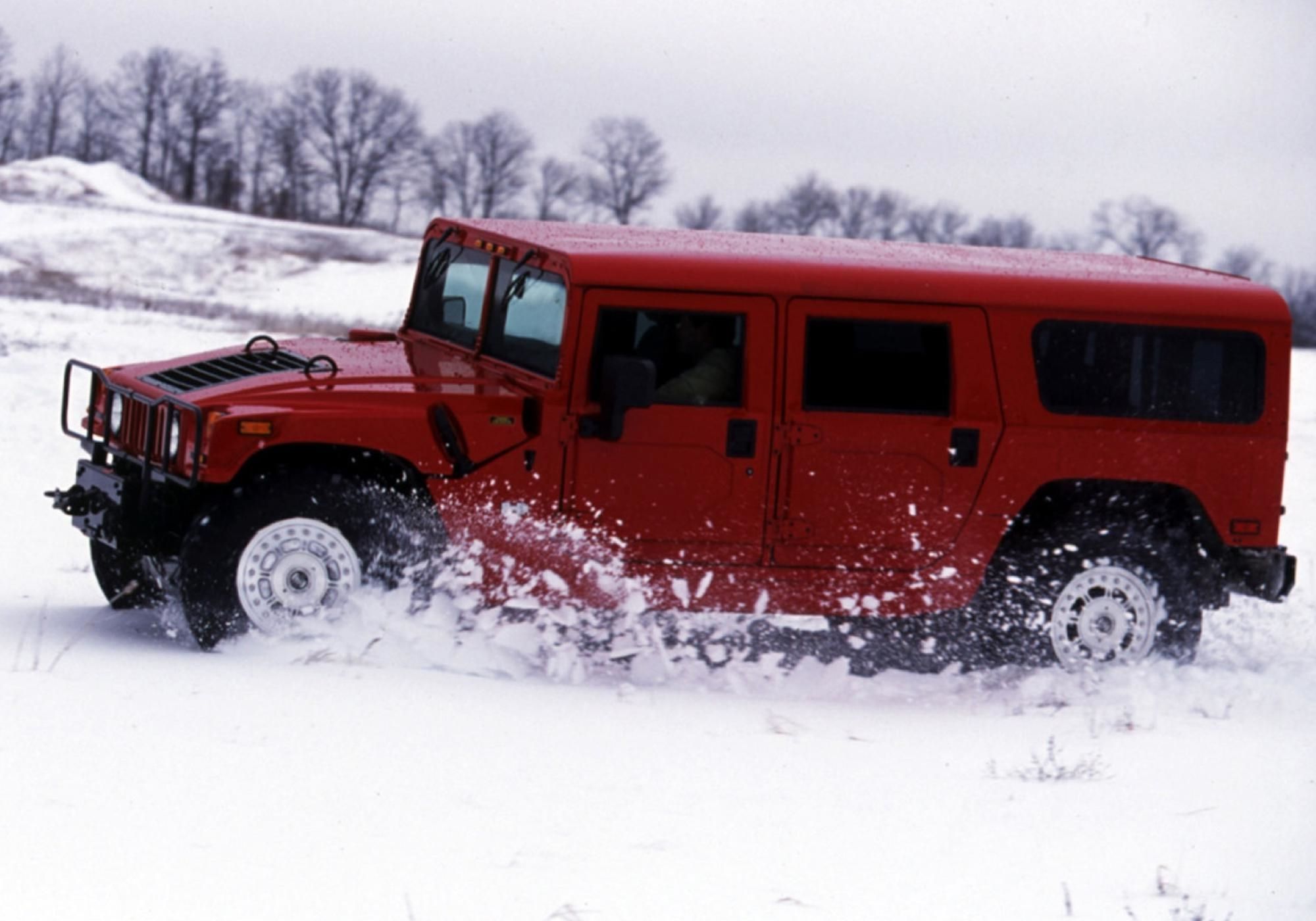 A Red 2003 AM General Hummer H1 driving on snow