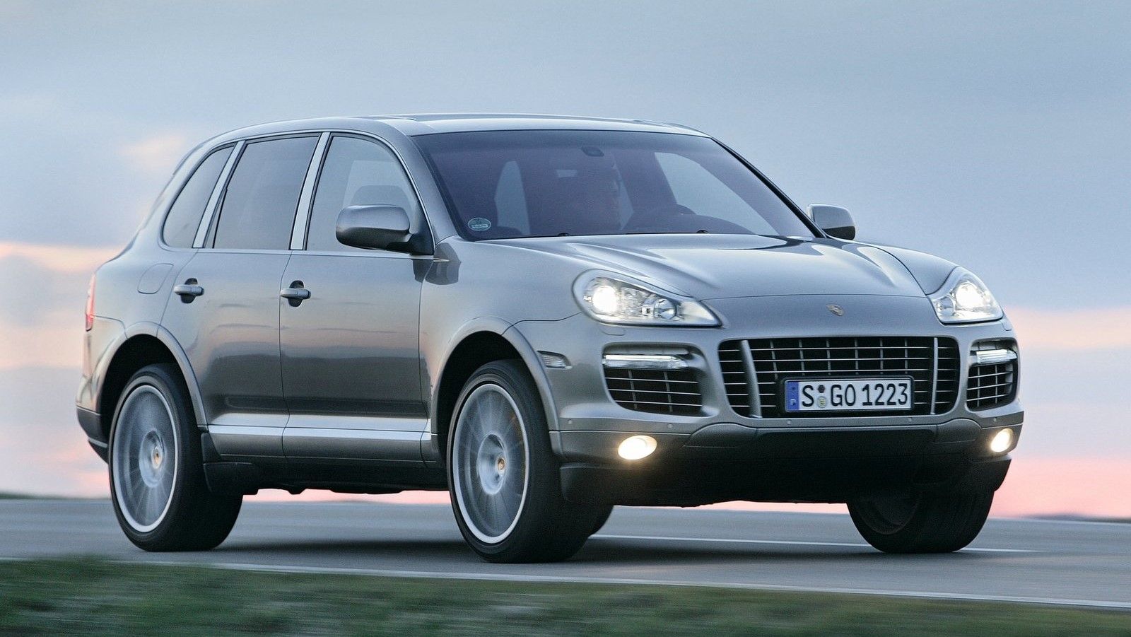 A silver 2009 Porsche Cayenne GTS driving down a country road.