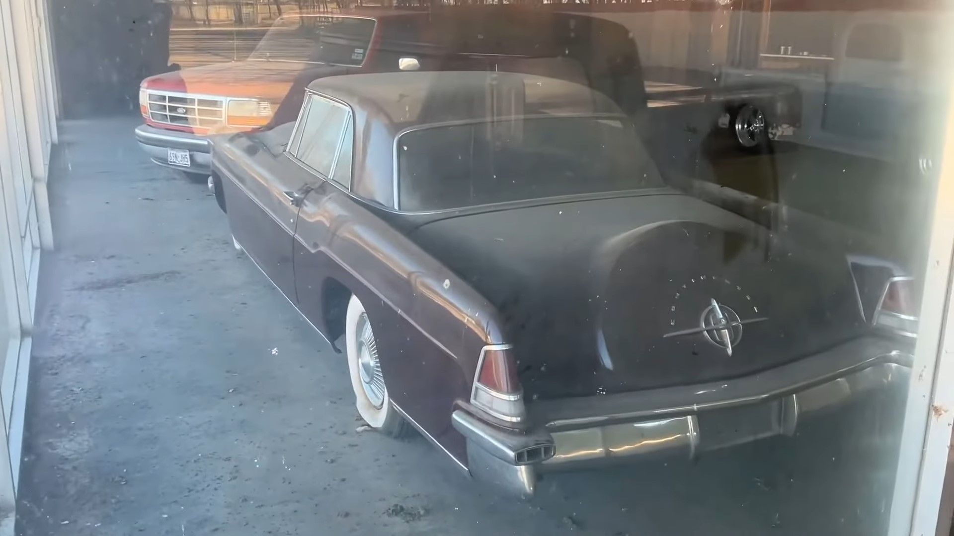 A red 1956 Lincoln Continental Mark II in an abandoned showroom rear quarter shot