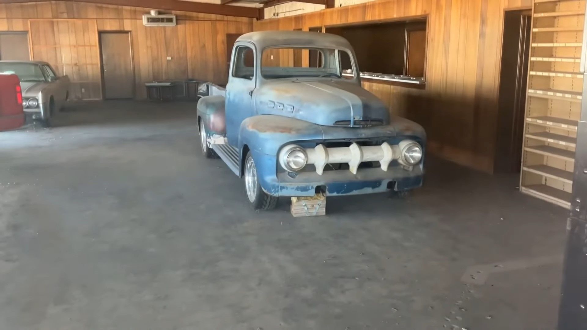 A blue 1951 Ford F-1 Pickup in an abandoned showroom front quarter shot