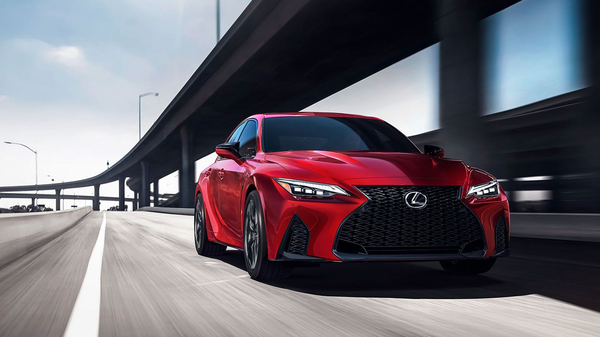 Red Lexus IS 500 F Sport drives by highway overpass