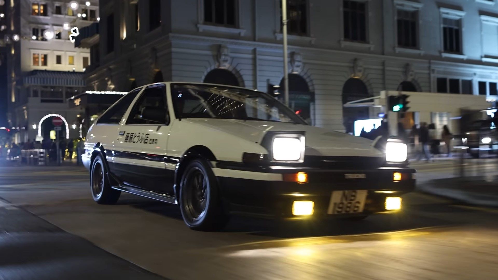 A white and black initial D style 1984 Toyota Corolla AE86 front quarter rolling shot