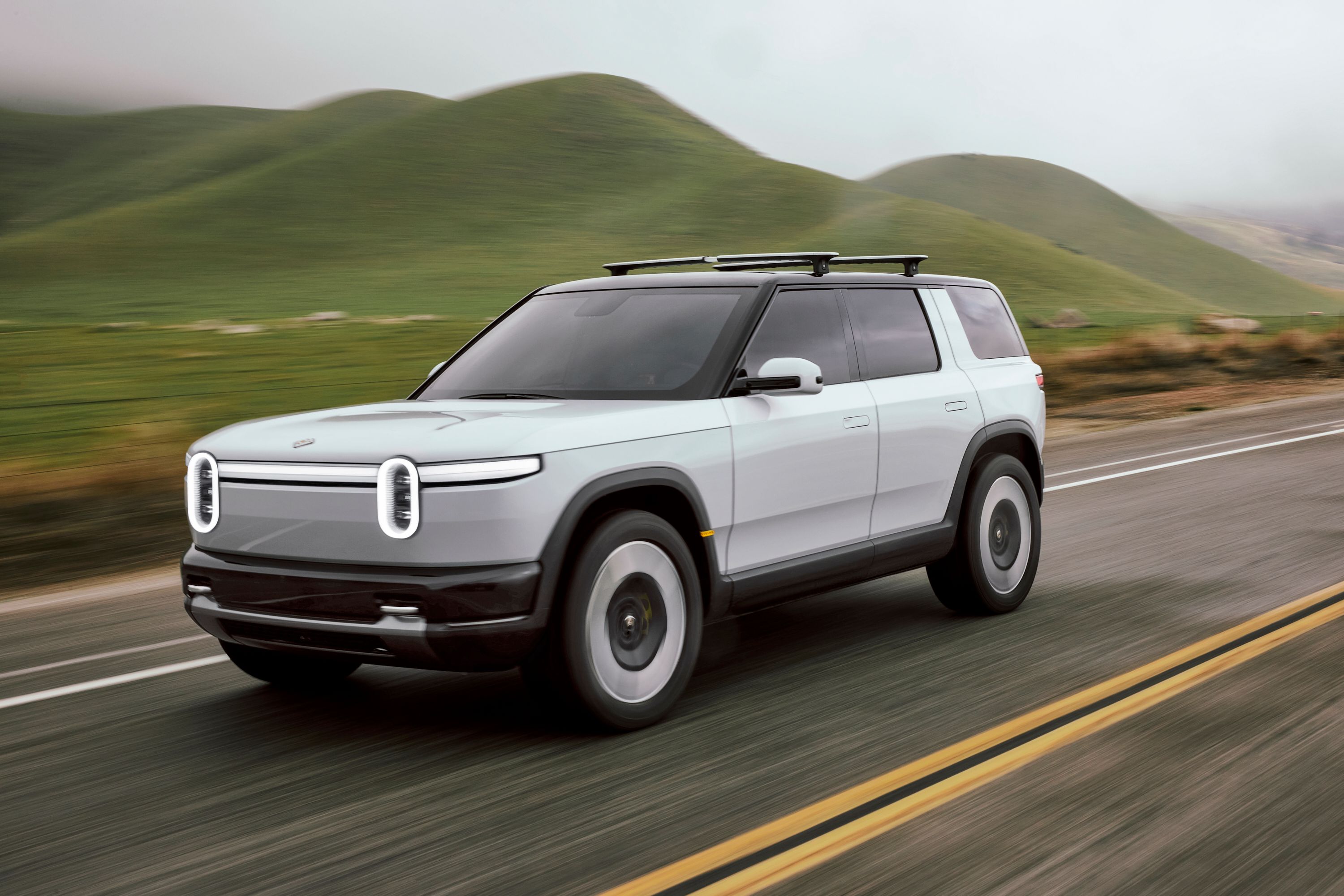 White Rivian R2 dirigindo em estrada secundária