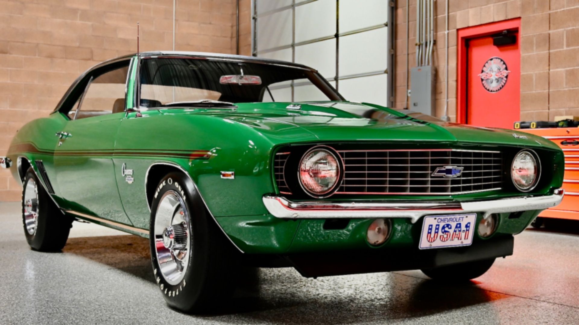 1969 Chevrolet Camaro Yenko/SC COPO L72 427/425 4 velocidades na cor verde em um prédio com porta vermelha e portão de garagem.