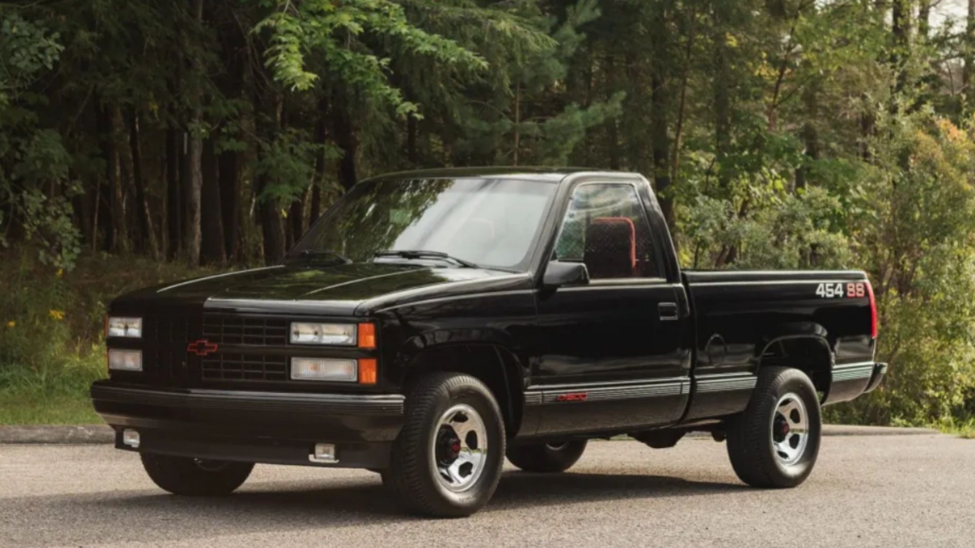Pickup Chevrolet 454 SS 1990 em preto próximo a uma floresta.