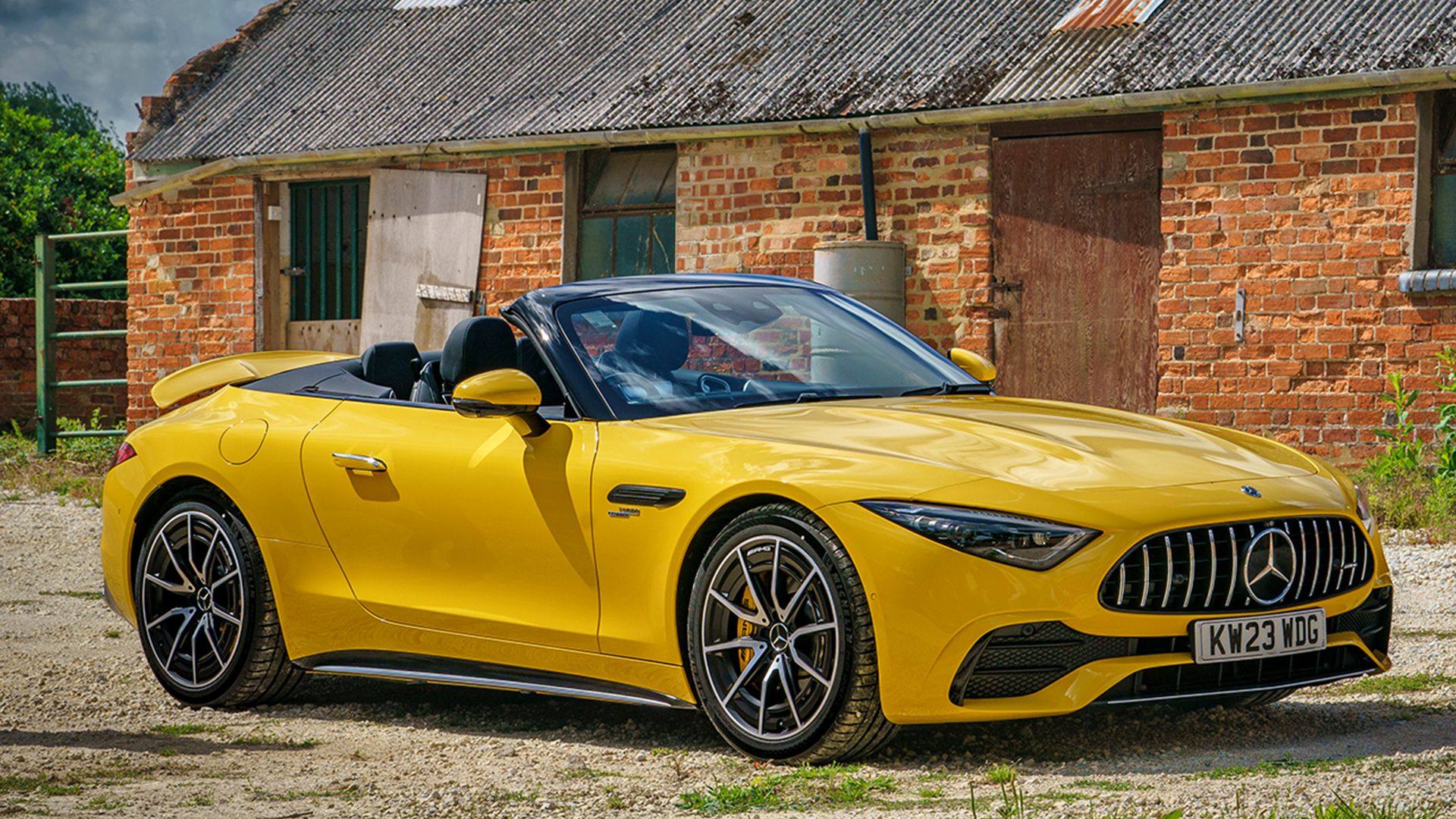 yellow 2024 Mercedes-AMG SL 43 Roadster parked front of farmhouse 