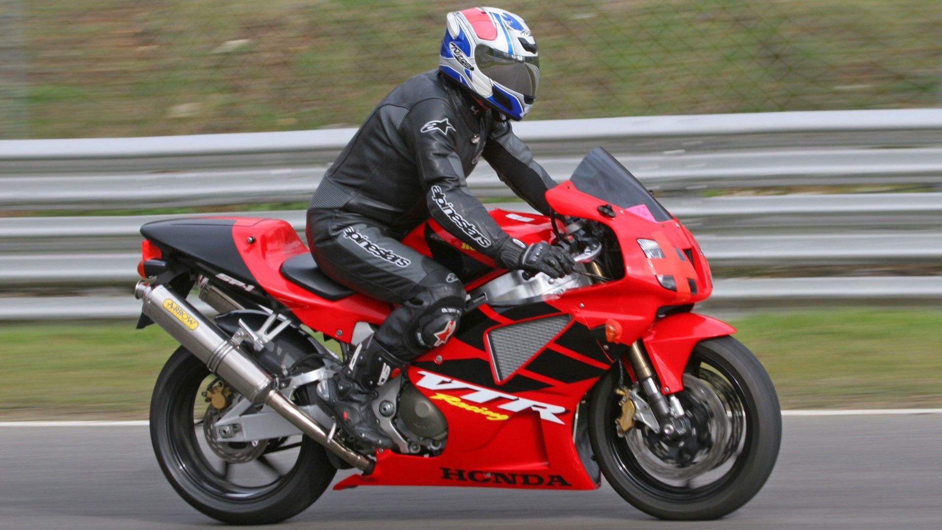 Honda VTR 1000 SP1 on a racetrack accelerating side profile view