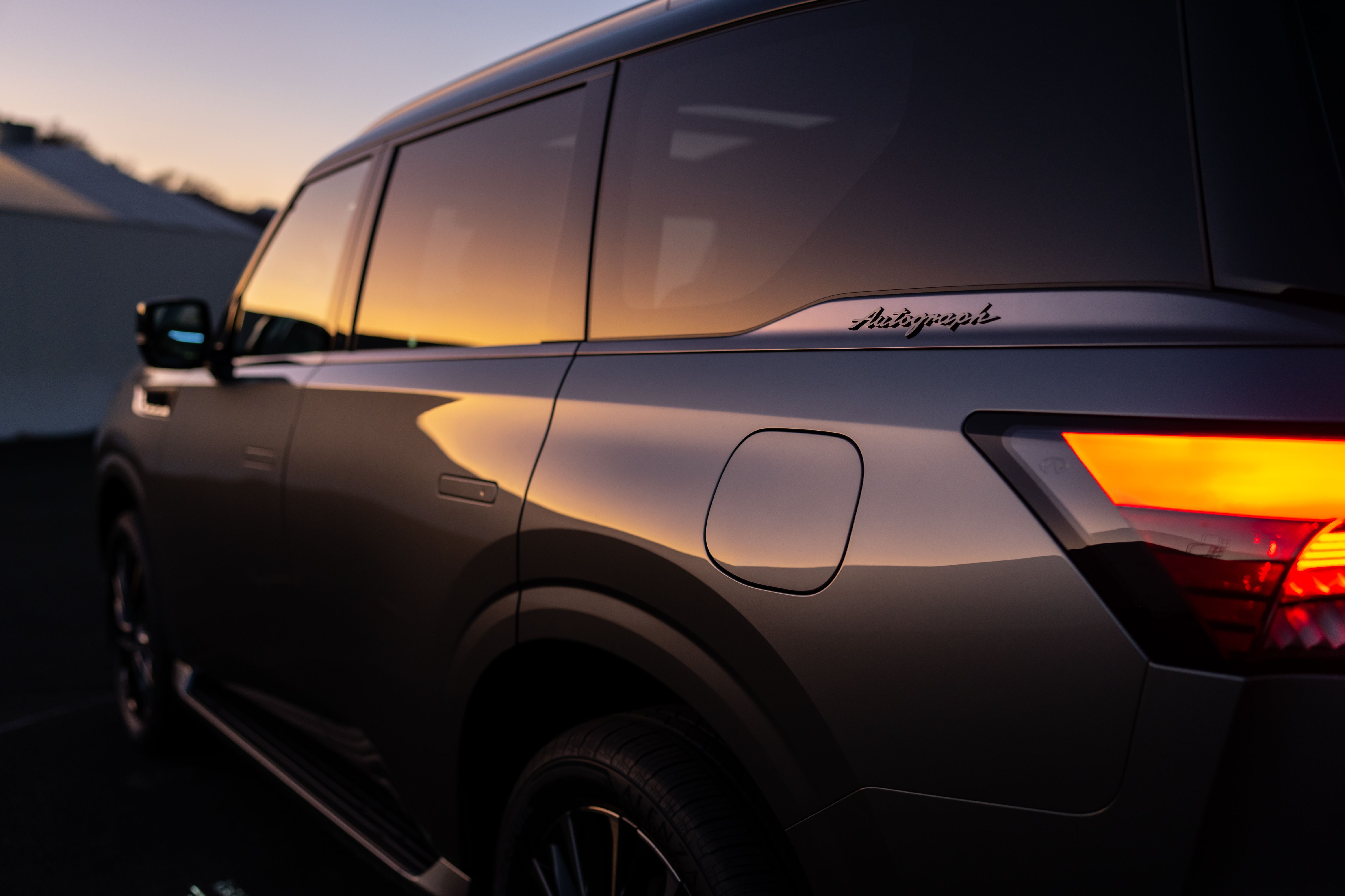 Prata 2025 Infiniti QX80 ao pôr do sol com logotipo Autograph visível