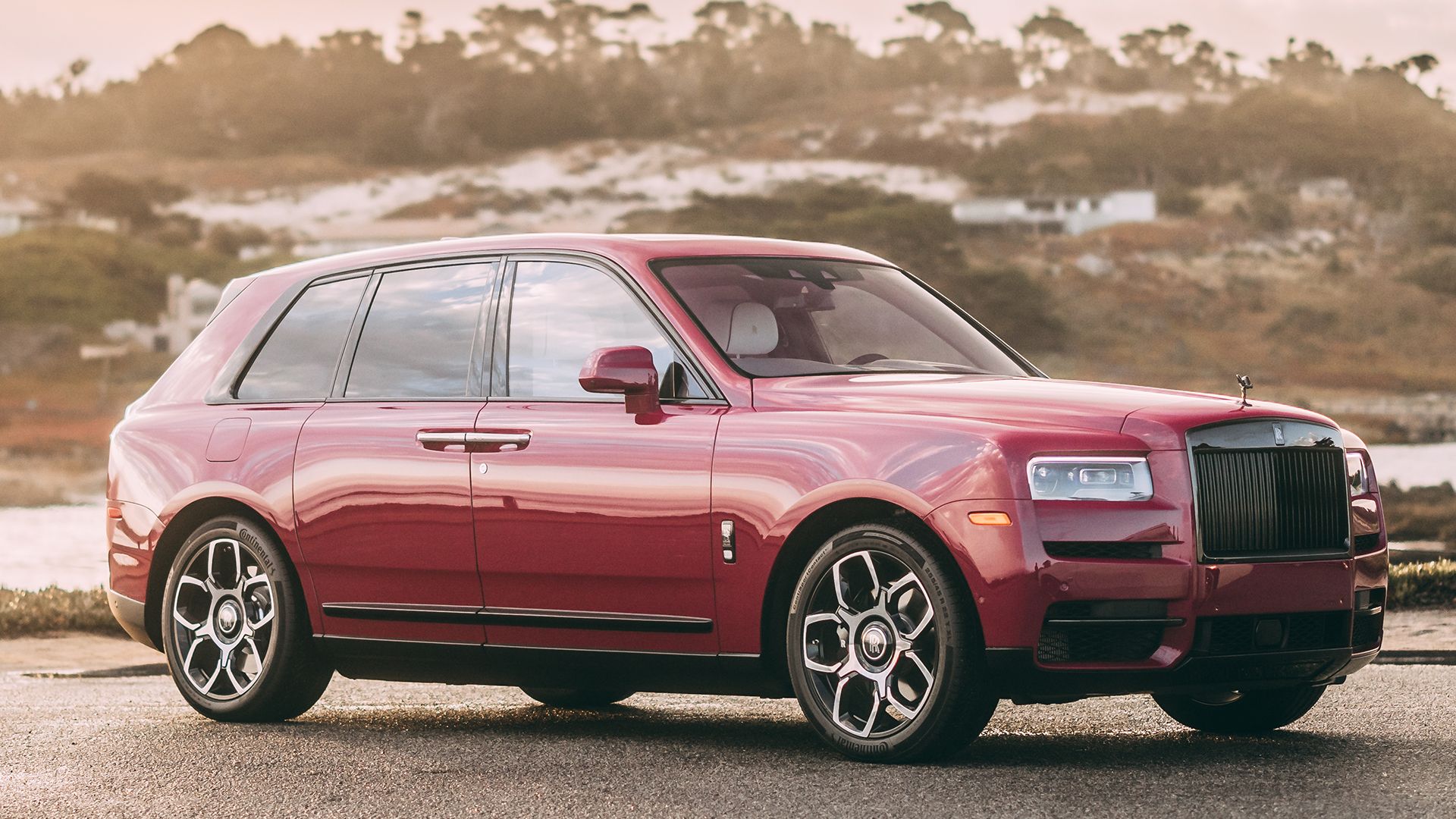 pink Rolls-Royce Cullinan park beside a road