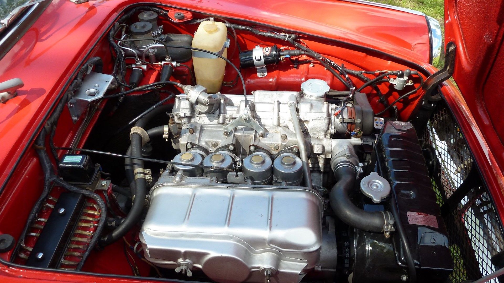 A red 1965 Honda S600 Roadster engine bay side shot